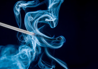 Burnt match with magic smoke on black background