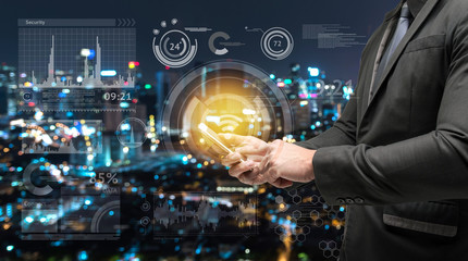 Business man suit using smart phone and Technology graphic with blur bokeh city background. Smart city and internet of things concept.