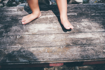 Little girl barefoot closeup of a foot on a plank background.