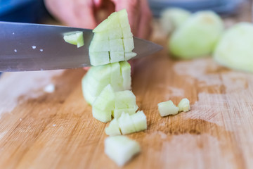 Cook chopping green peeled granny smith apples on board with large knife