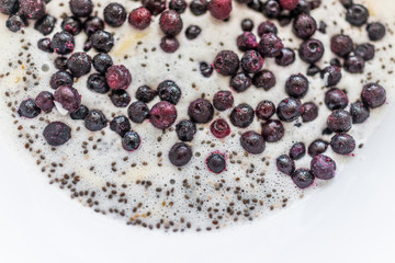 Frozen blueberries and chia seeds floating on milk