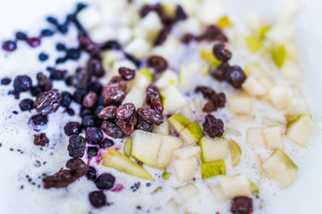 Pears, raisins and blueberries in bowl with milk macro closeup