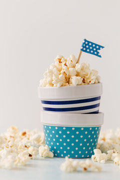 Homemade buttered popcorn served in colorful bowls decorated with party flags. 
