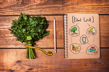 Blank notebook and pencil with a bunch of herbs on wooden table