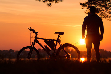 Fototapeta na wymiar Cyclist at sunset .Bike at sunset near the lake under a pine tree