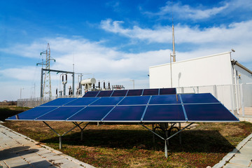 Solar panels in power station against wind turbines background - concept of sustainable resources