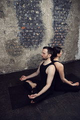 Young athletic couple practicing acroyoga. Balancing in pair. Fit active pair yoga time. Sporty handsome man supporting and holding slim beautiful brunette woman. Training time. Asana 