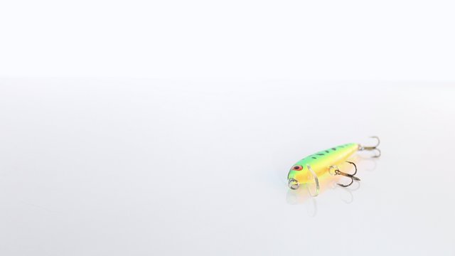 Green and Yellow Colored Fish Lure on a Plain Background