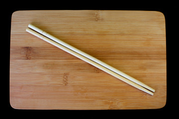 Japanese chopsticks on wooden board isolated on black background.