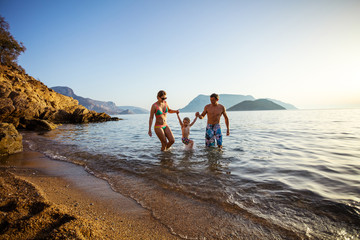 Caucasian family of three having fun on beach