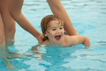 Fototapeta na wymiar Cute baby boy learns to swim with mothers help