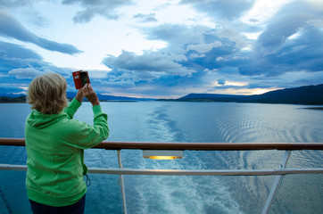 Cruise ship passenger photographs the sunrise with her smart phone. - 140102594