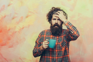 Bearded man with stylish fringe hair holding blue cup