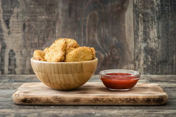 Fried chicken nuggets in bowl on wooden table
