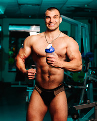 Fototapeta na wymiar Handsome athletic fitness man holding a shaker and posing gym