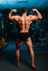 Fototapeta na wymiar Bodybuilder stands with his back in the gym