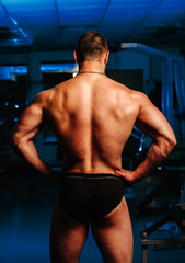 Fototapeta na wymiar Bodybuilder stands with his back in the gym