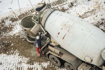 Concrete mixer truck pouring liquid concrete into the tower crane bucket