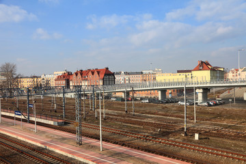 Szyny kolejowe, perony na dworcu w Opolu, zabytkowe kamienice.