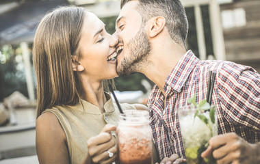 Handsome man kissing young woman at fashion cocktail bar - Happy couple of lovers at beginning of...