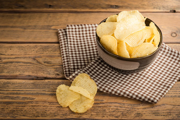 Potato chips in cup on wood background.