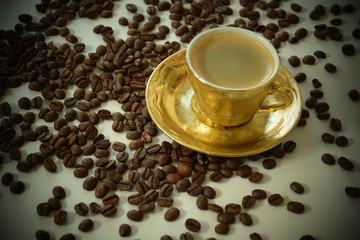 Goldene Tasse mit Kaffee und Kaffeebohnen 
