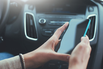 Close-up of woman's hands holding smartphone in the car interior