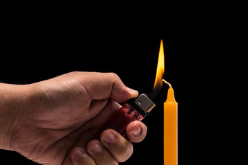 Hand holding burning gas lighter to light candle. Studio shot isolated on black background