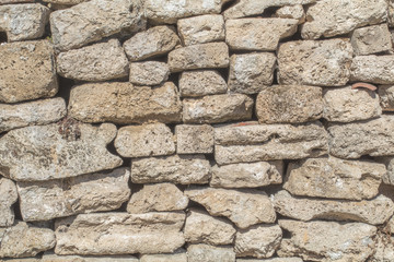 Ancient antique stone wall of medieval monastery or fortress. vintage background texture of masonry stone cement with cracks. Building facade.