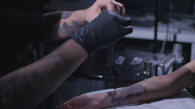Slow motion. tattoo artist wears black gloves sterile. Preparing tattoo artist to work. Tattoo parlor. tattoo artist wears gloves