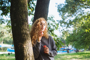 young attractive female blowing soap bubbles in park, portrait