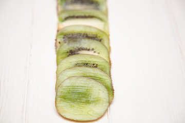 Sliced kiwi slices on a light wooden background