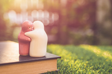 White and pink ceramic doll on book with blur bokeh and sunlight