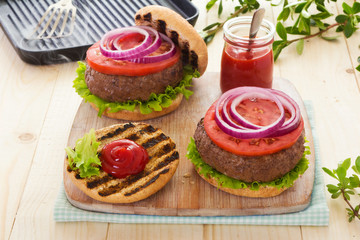 Grilled burgers with tomatoes and red onions on buns