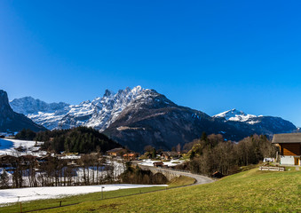 Fototapeta na wymiar Alpine natural landscape with green fields, high rocks and white clouds