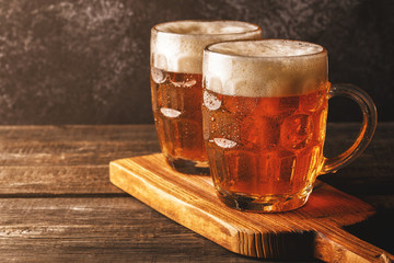 Cold beer in glass with chips on a dark background.