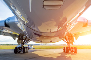 Large modern airplane view from bottom to bottom and landing gear, light sun