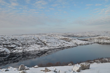The lake is surrounded by cliffs covered with snow.