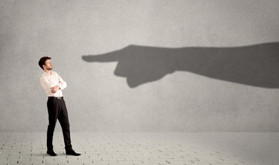 Business person looking at huge shadow hand pointing at him concept