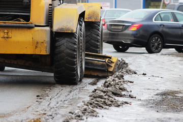 tractor cleans the road in the city of dirty snow