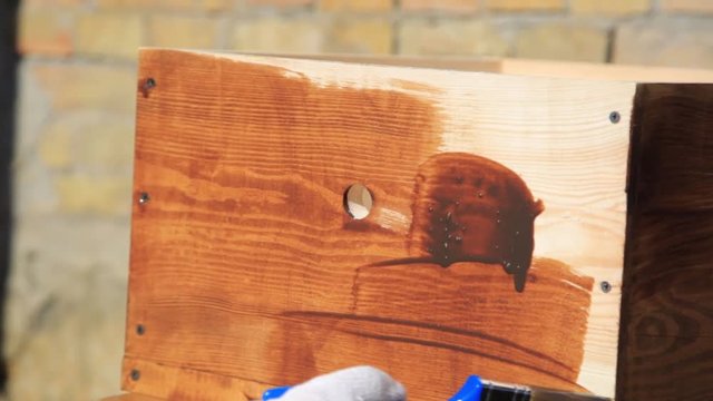 Close-up Wood painting with a brush with the brown color. DIY do it yourself concept.