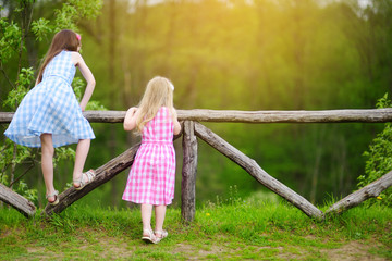 Naklejka na ściany i meble Two little sisters having fun on warm and sunny summer day