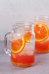 Orange cocktail garnished with thyme in jars