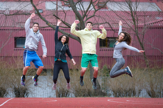 your young people two girls and two boys happy smiling in joyful  jump outdoors ina basketball court,