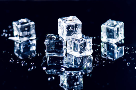 Iced Cubes Melting On A Black Table With Reflection. Water. Melting Of Ice. 