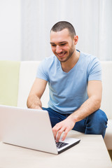 Young man is using laptop at his home.