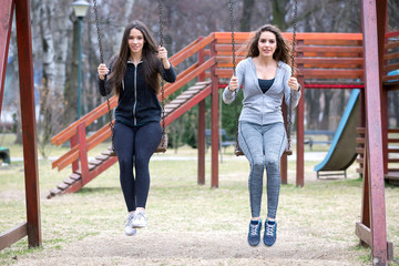 two young woman swinging in a park