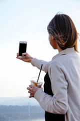 A young female taking a selfie and drinking milkshake.