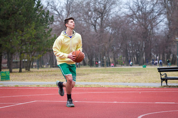 Obraz premium one ypung man plays basketball in a park