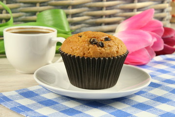 Chocolate muffins with a Cup of coffee and flowers on the table